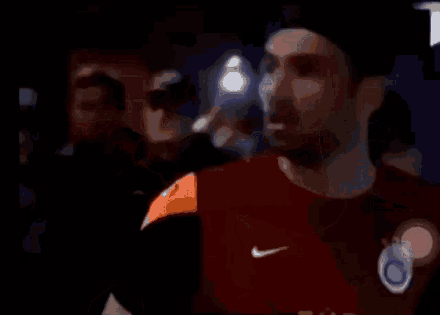 a man in a red nike shirt talks to another man
