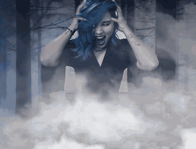 a woman with blue hair and a tattoo on her arm is screaming in a foggy forest