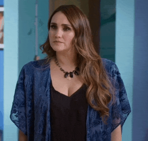 a woman wearing a black top and a blue kimono is standing in front of a blue wall