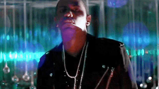 a man wearing a black leather jacket and a necklace is standing in front of a bar .