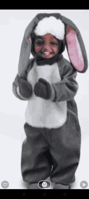 a child is dressed in a bunny costume with a pink ear