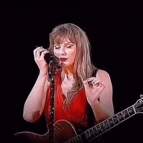 taylor swift is holding a guitar and singing into a microphone on stage .