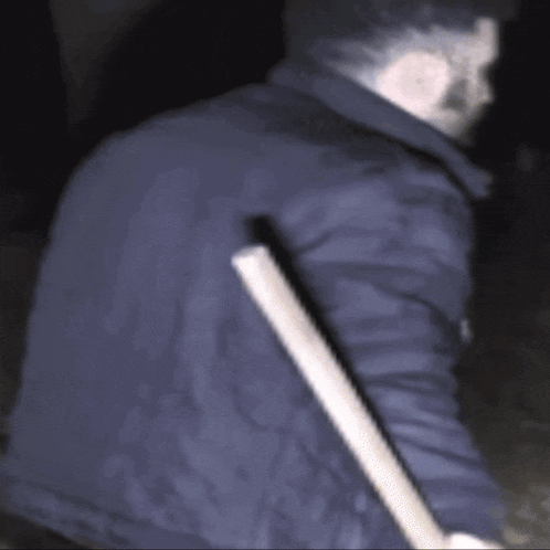 a blurry picture of a man in a blue jacket holding a stick