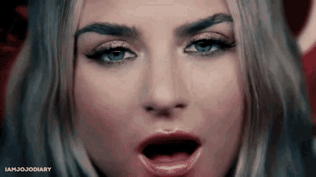 a close up of a woman 's face with her mouth open and a surprised look on her face .