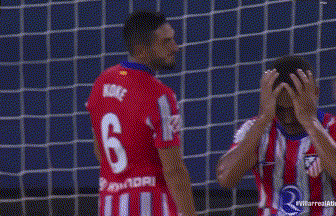 a group of soccer players are standing in front of a goal and one of them is holding his head .