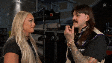 a man and a woman are looking at each other and the man has a mustache
