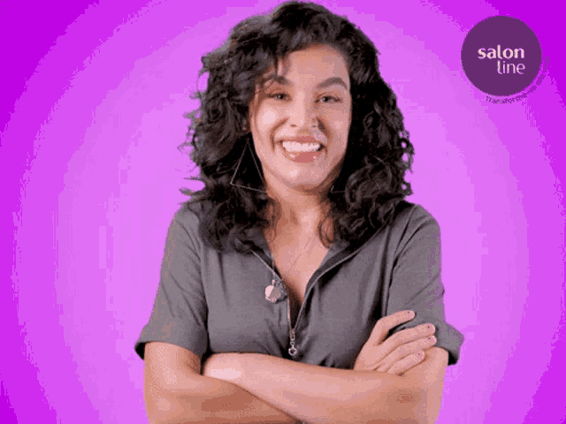 a woman with her arms crossed is smiling in front of a purple background that says salon line