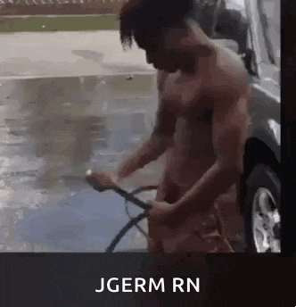 a shirtless man is washing a car with a hose