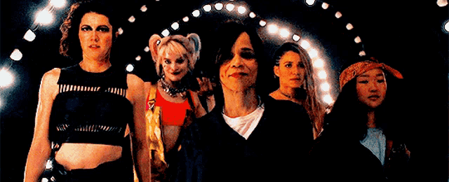 a group of women are standing next to each other in front of a stage .