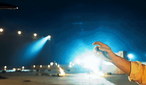 a person 's hand is reaching out towards a bright light in the sky