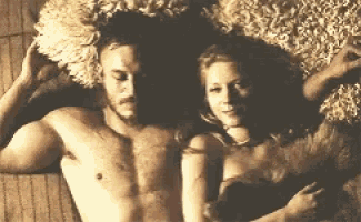 a man and a woman are laying on a blanket on a bed .