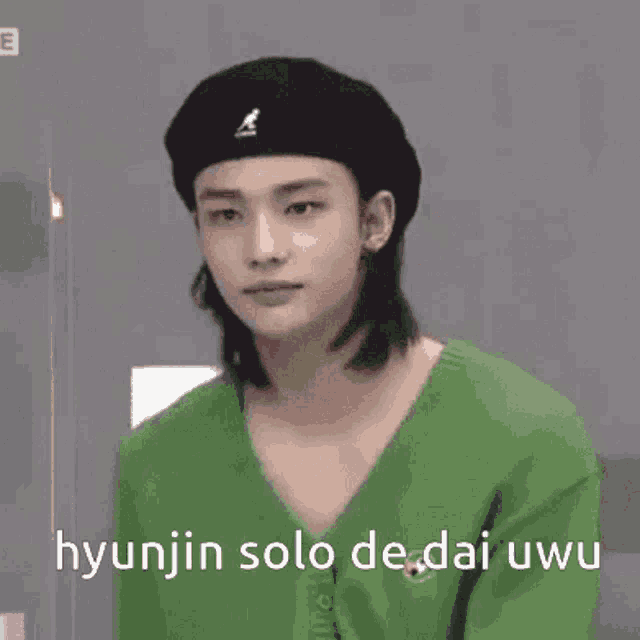 a man wearing a green sweater and a black beret is making a funny face .