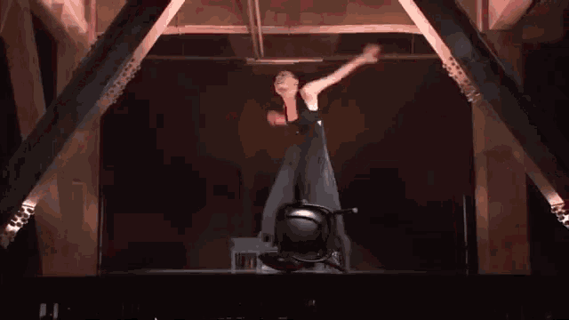 a man is hanging upside down from a beam in a dark room