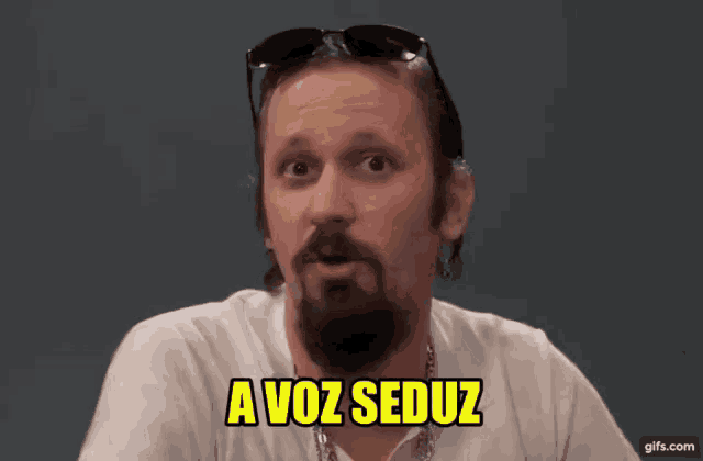 a man with a beard wearing sunglasses and a white shirt says a voz seduz