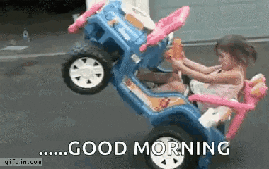 a little girl is driving a toy car on a street .
