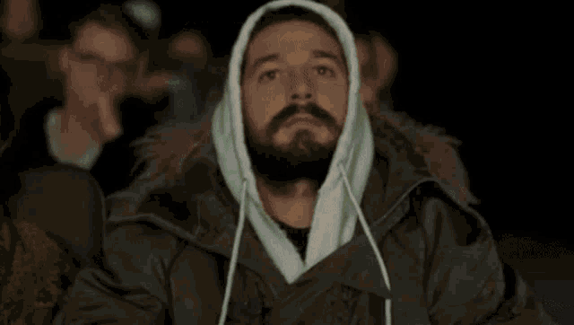 a man with a beard is sitting in a theater watching a movie and smiling .