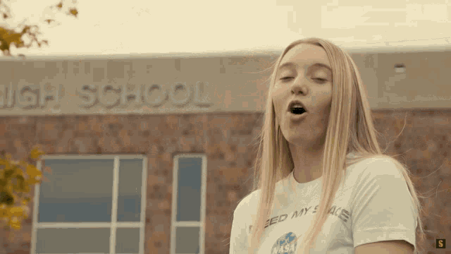 a woman singing in front of a high school building