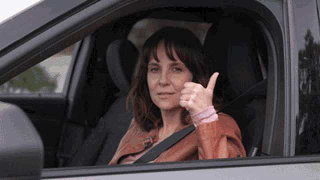 a woman giving a thumbs up in a car