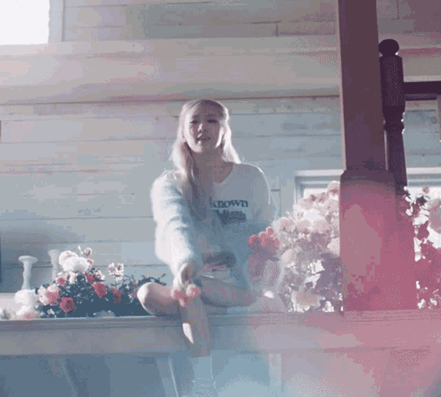 a woman wearing a sweater that says known sits on a balcony
