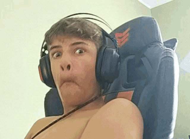 a shirtless man is wearing headphones while sitting in a chair .