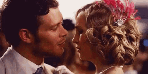 a man and a woman are kissing in front of a crowd .