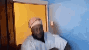 a man in a white robe and hat is standing in front of a door .