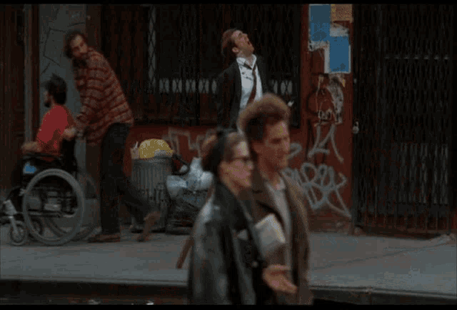 a person walking down a street with graffiti on the wall and a trash can that says ' graffiti ' on it