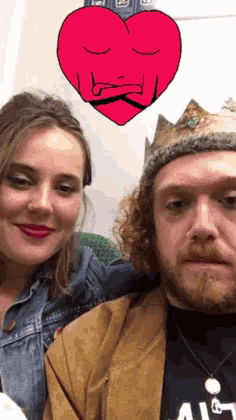 a man and a woman are posing for a picture with a red heart behind them