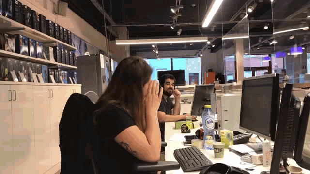 a woman sits at a desk with a bottle of aquafina water in front of her