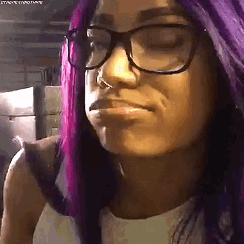 a woman with purple hair and glasses making a funny face .