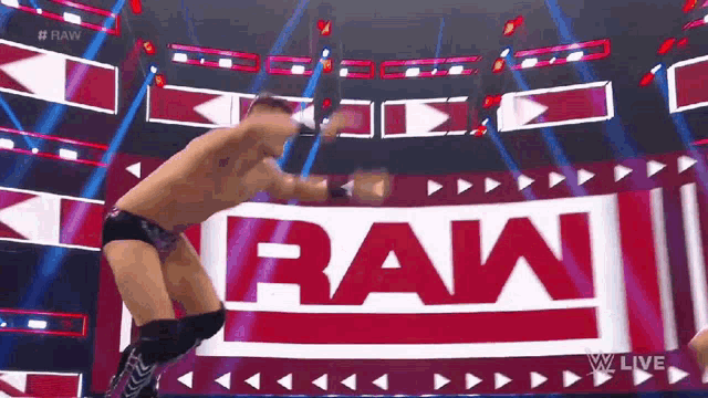 a man is jumping in the air in front of a sign that says raw .