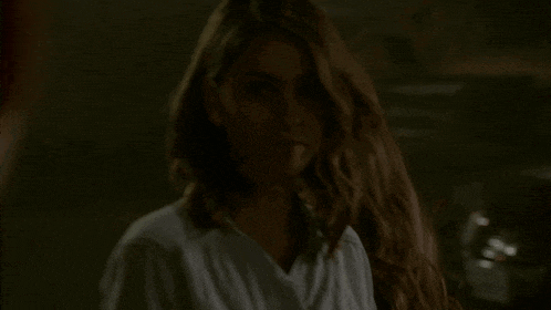 a woman with long hair is standing in a dark room looking at the camera .