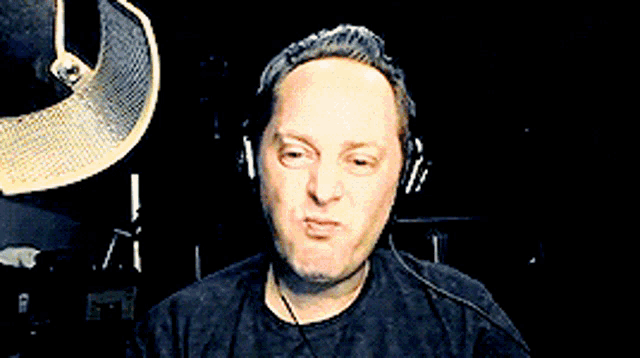 a man wearing headphones is standing in front of a microphone with his hands outstretched