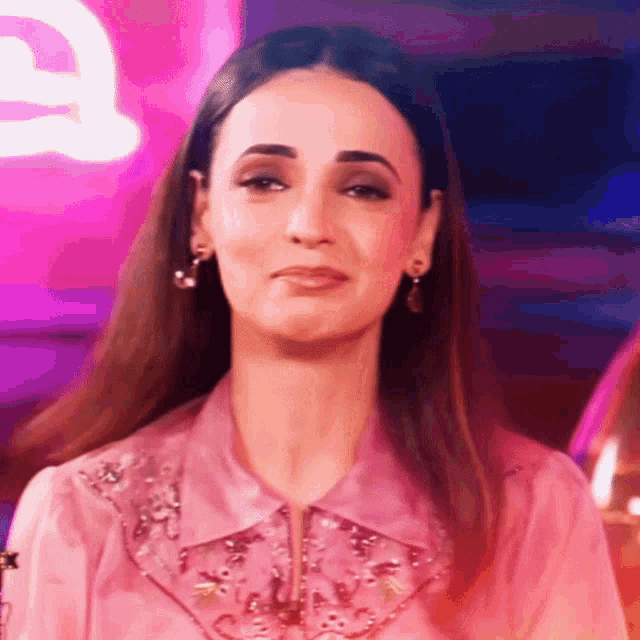 a woman is wearing a pink shirt and earrings