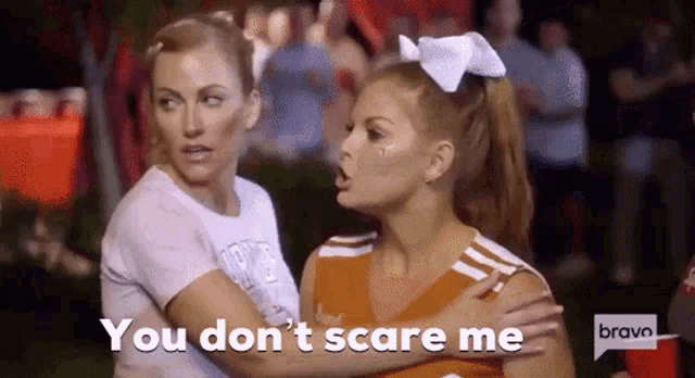 two cheerleaders are standing next to each other and talking .