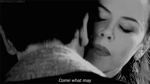 a black and white photo of a man and woman kissing with the words `` come what may '' written below them .
