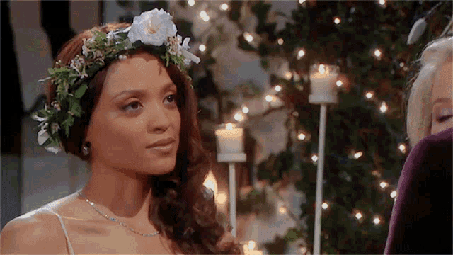 a woman with a flower crown on her head is standing in front of candles .