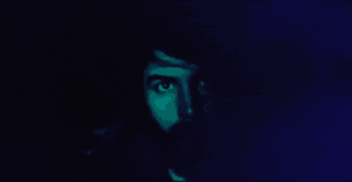 a close up of a man 's face with a beard in a blue light