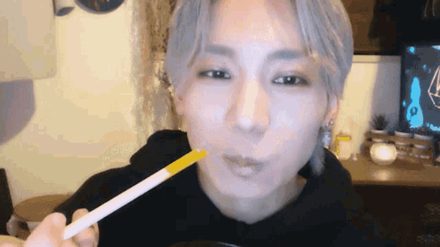 a man with gray hair is holding a yellow stick in his mouth
