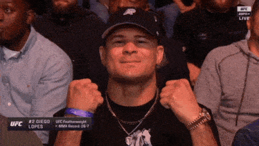 a man wearing a hat and a watch is sitting in a crowd watching ufc