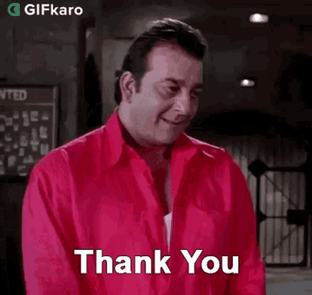 a man in a red shirt is giving a thank you gesture .