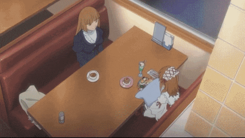 two girls sit at a table in a diner with plates of food