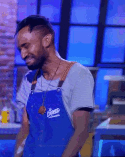 a man is wearing a blue apron that says cooked