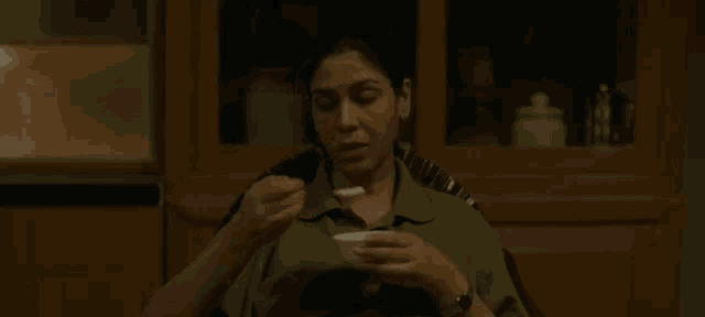 a woman is sitting in a chair eating food from a bowl .