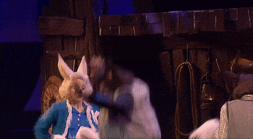 a man in a blue and white costume with bunny ears is talking to another man