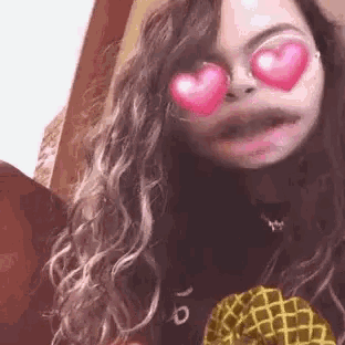 a woman with heart shaped sunglasses on her eyes is holding a pineapple .