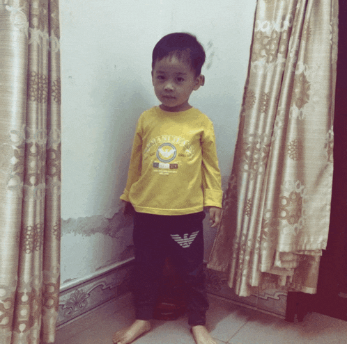 a young boy wearing a yellow shirt that says ' emporio armani ' on the front