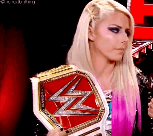 a woman with blonde hair is holding a red and gold wrestling championship belt .