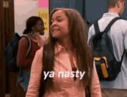 a woman with a backpack is standing in a hallway and says ya nasty .