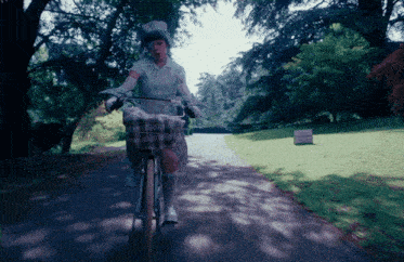 a woman is riding a bike down a path with a sign that says " no parking " in the background